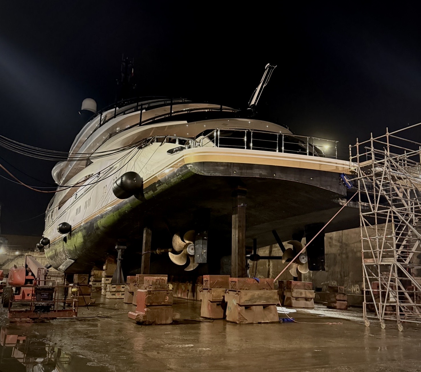 Large motor yacht blocked ashore during nighttime shipyard work