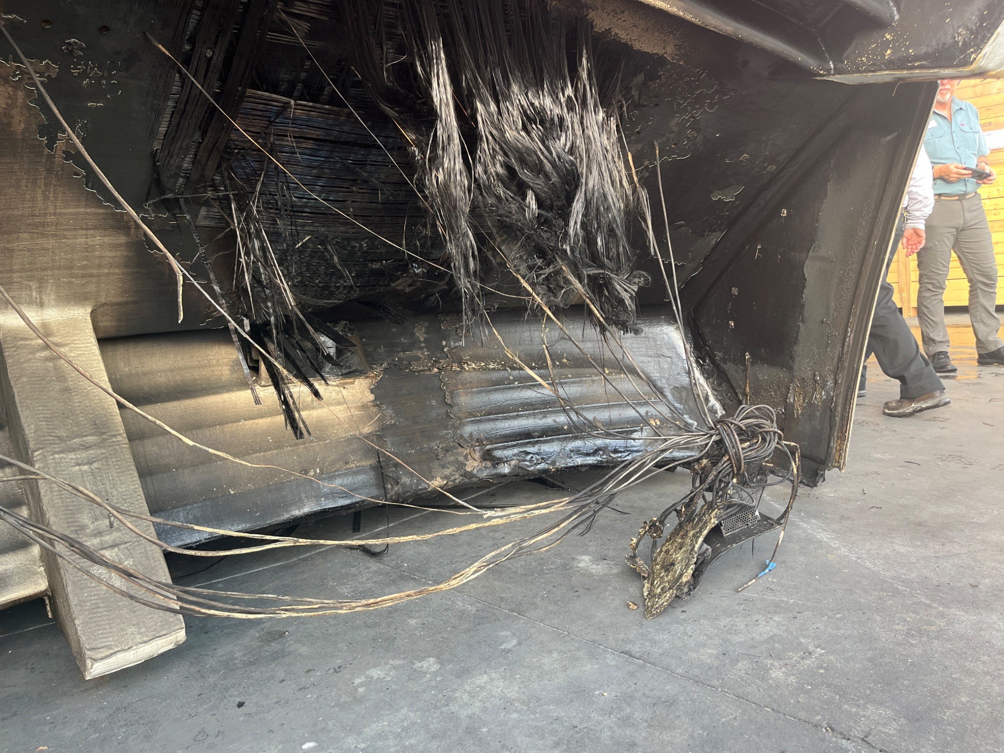 Fire-damaged yacht structure with exposed reinforcement and cabling